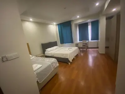 a room with two beds and a table and chairs at Birinci Apart Hotel in Istanbul