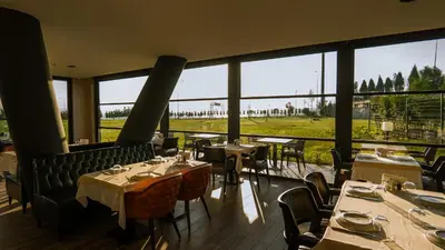 a restaurant with tables and chairs and large windows at Motel Heksapolis in Tavşancıl