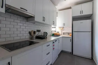 a kitchen with white cabinets and a white refrigerator at 2BR Bright Kadıköy Apartment & AC in Every Room in Istanbul