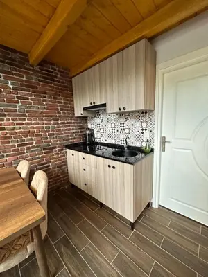 a kitchen with wooden cabinets and a brick wall at ROSE SAPANCA STONE HOUSE in Sakarya