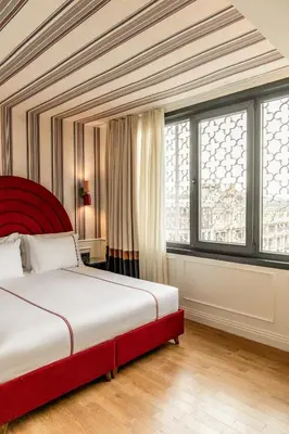 a bedroom with a bed with a red headboard and windows at Khai Karaköy in Istanbul