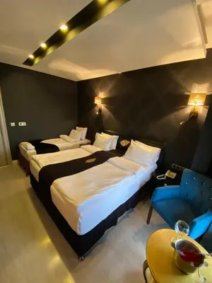 a hotel room with two beds and a blue chair at Golden Gate Hotel Topkapı in Istanbul