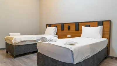 two beds in a hotel room with white sheets at GRAND MOON HOTEL in Esenyurt