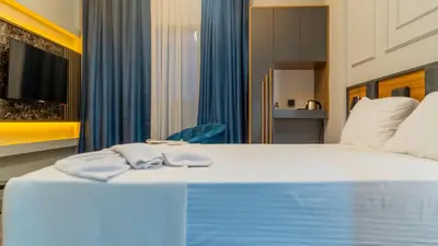 a bedroom with a large white bed with blue curtains at GRAND MOON HOTEL in Esenyurt