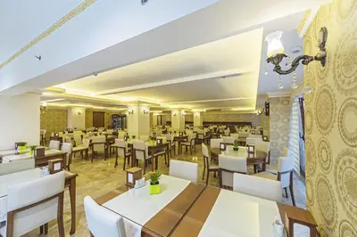 a restaurant with white tables and white chairs at Lausos Palace Hotel Şişli in Istanbul