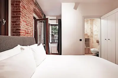 a bedroom with a white bed and a brick wall at Homie Suites - Modern Apartments Nearby Istıklal Street & Galata Tower in Istanbul