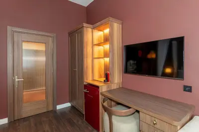 a bedroom with a tv on a pink wall with a bench at CLK Suites Hotel in Istanbul