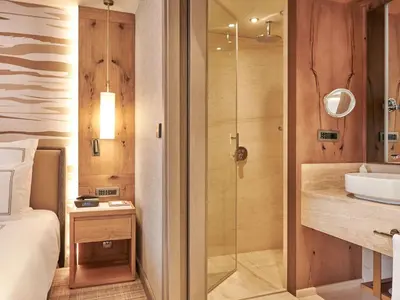 a bathroom with a shower and a sink and a bed at Swissotel Uludag Bursa in Bursa
