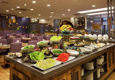 a buffet line with plates and bowls of food at Hilton Garden Inn Kocaeli Sekerpinar in Şekerpınarı