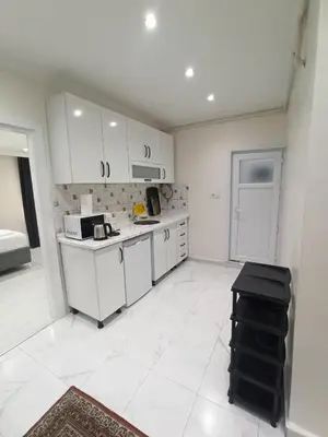 a kitchen with white cabinets and a white tile floor at CEM Apart in Istanbul