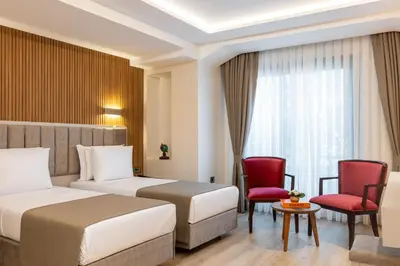 a hotel room with two beds and red chairs at Carina Gold Hotel And Restaurant in Istanbul
