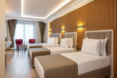 a hotel room with three beds and a table and chairs at Carina Gold Hotel And Restaurant in Istanbul