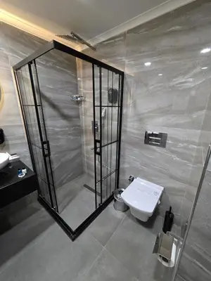 a bathroom with a shower and a toilet and a sink at Gardan Hotel in Beylikduzu