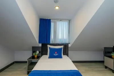 a bedroom with a bed with a blue pillow on it at The Great Airport Hotel & Restaurant in Arnavutköy