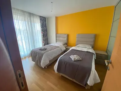 a bedroom with two beds and a yellow wall at TAKSiM PERFECT RESiDENCE, 3 BEDROOMS, 140 M2, POOL GYM SAUNA ACCESS in Istanbul