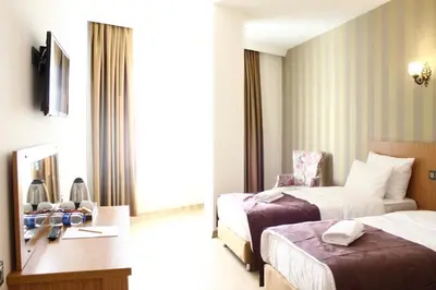 a hotel room with two beds and a desk at Melidium Hotel in Beylikduzu
