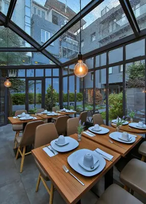 a restaurant with wooden tables and chairs and windows at Alilass Hotel in Istanbul
