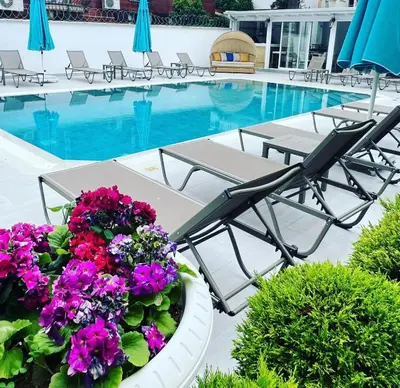a patio with chairs and flowers next to a swimming pool at Villa No 44 in Darıca