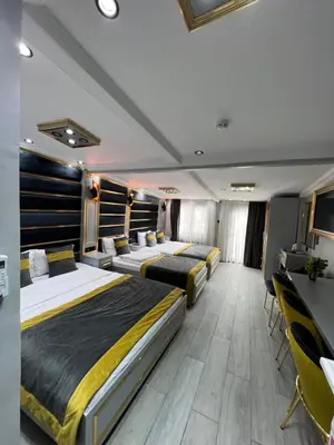 two beds in a room with a desk and chairs at TAKSİM LARİSSA RESİDENCE in Istanbul