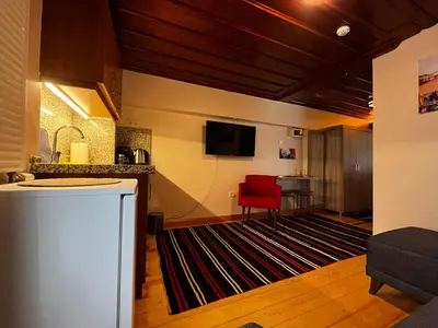 a living room with a kitchen and a red chair at Lily Mansion in Istanbul