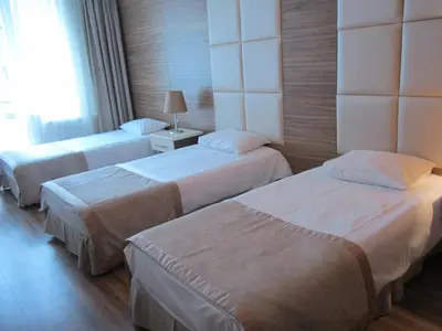 a hotel room with three beds and a window at Derpa Suite Hotel in Istanbul