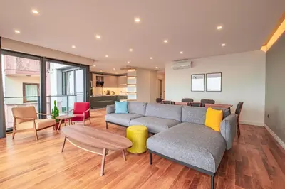 a living room with a couch and tables and chairs at Homie Suites - Newly Built Seaside Apartments on Bakırköy Shore in Istanbul