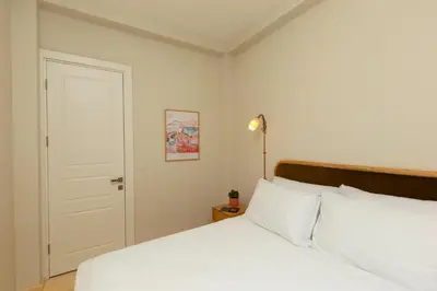 a bedroom with a bed with white sheets and a door at Lemon Apartments in Istanbul