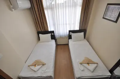 two beds sitting in a room with a window at Hotel Baykal in Istanbul