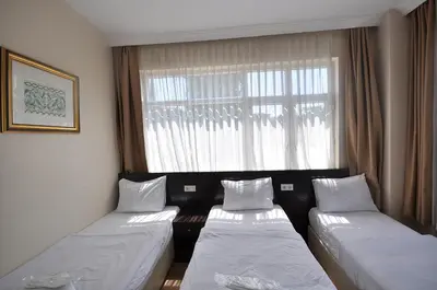 two beds in a room with a window at Hotel Baykal in Istanbul