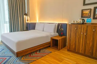 a bedroom with a large bed and a wooden cabinet at Hampton By Hilton Sakarya in Sakarya