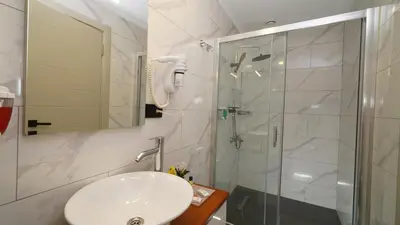 a white bathroom with a sink and a shower at The Marist Hotel Kadikoy in Istanbul