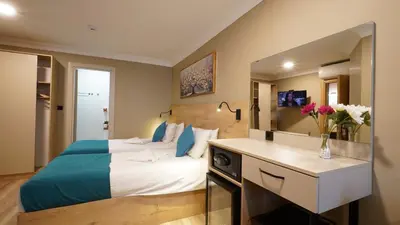 a hotel room with a bed and a desk with flowers at The Marist Hotel Kadikoy in Istanbul