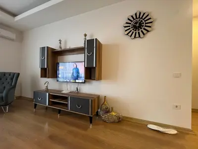 a living room with a television and a clock on the wall at Cozy Homes 1 Room 1 Living room Apartment in Esenyurt