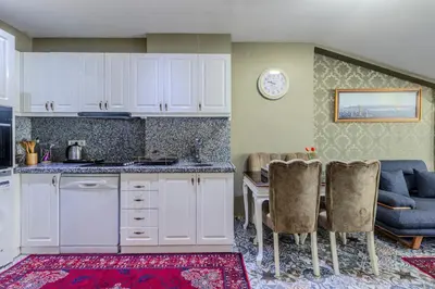 a kitchen with white cabinets and a table and chairs at Lemis Suite Istanbul in Istanbul
