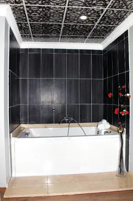 a white bath tub in a room with black tiles at Avist Hotel Avcılar in Avcılar