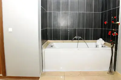 a white bath tub in a bathroom with black tiles at Avist Hotel Avcılar in Avcılar