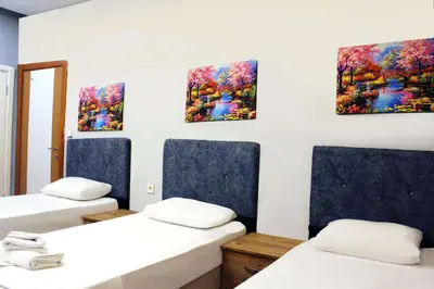 a room with three beds and three paintings on the wall at Avist Hotel Avcılar in Avcılar