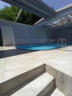 a large swimming pool with a patio and an umbrella at Grandvadi Villa kapalı ısıtmalı havuz in Sapanca