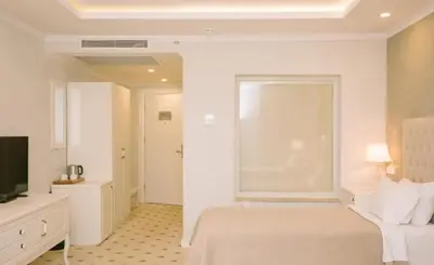 a white bedroom with a bed and a window at Burgaz İzer Hotel in Lüleburgaz