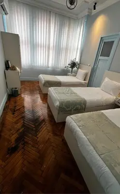 three beds in a room with wooden floors at Bali Star City Hotel in Istanbul