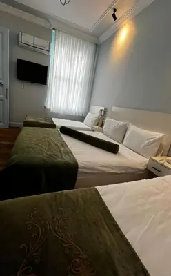 a hotel room with three beds and a window at Bali Star City Hotel in Istanbul