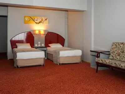 a hotel room with two beds and a chair at HOTEL EKEN in Bandırma