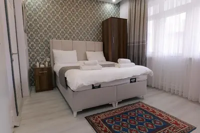 a bedroom with a bed with white sheets and a rug at Pera Apart in Istanbul