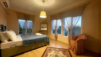 a bedroom with a bed and a chair and windows at Bizim Ev in Sapanca