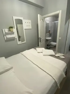 a bedroom with two white beds and a bathroom at Kadıköy Miski Amber in Istanbul