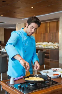 a man preparing food in a pan on a stove at Fesa Business Hotel in Gebze