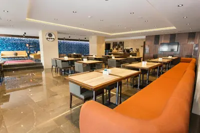 a restaurant with wooden tables and orange chairs at Fesa Business Hotel in Gebze