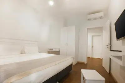 a white bedroom with a bed and a tv at Stay Juno in Istanbul