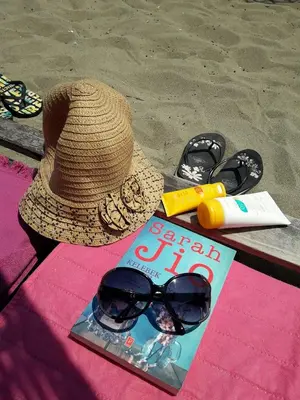 a hat and a book and sunglasses on the beach at The rooms hotel in Kumbağ