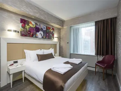 a hotel room with a bed and a red chair at Bilek Hotel Kavacık in Istanbul